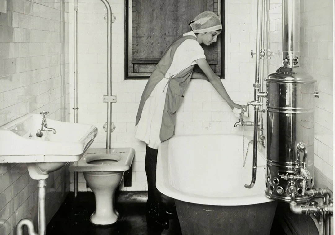 Side view of a young male employee holding a stack of white towels while standing in the bathroom of a luxury hotel